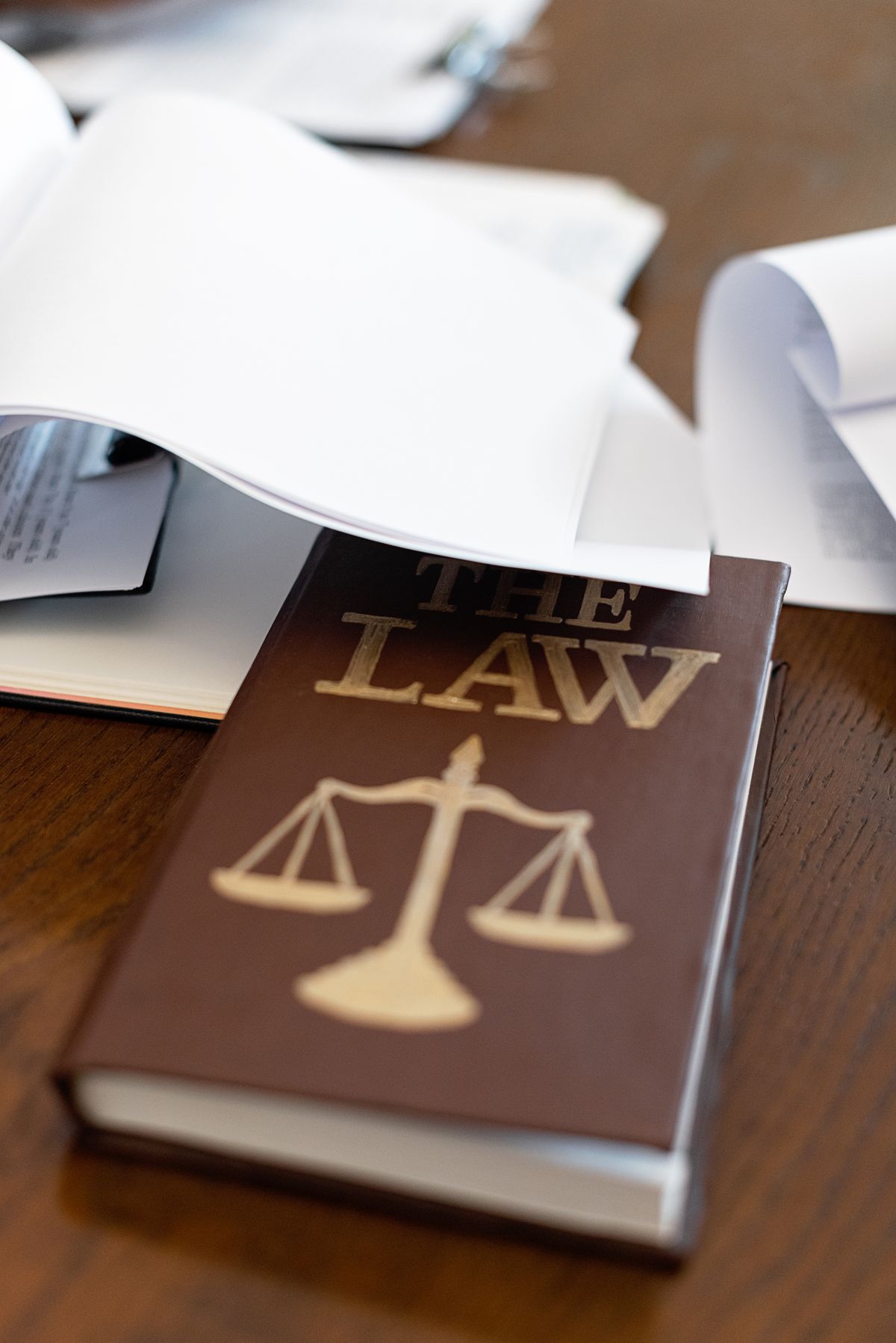 An open law book on a wooden desk beside loose papers