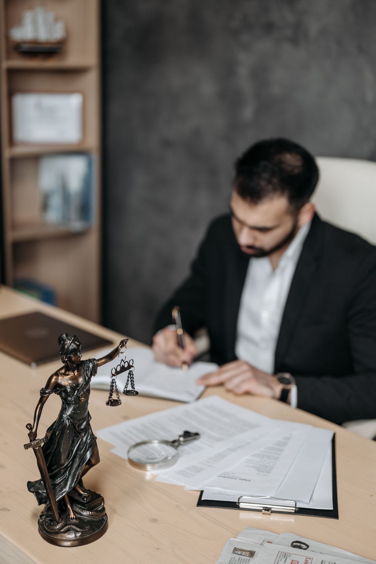 A lawyer in a dark suit writing on a sheet of paper